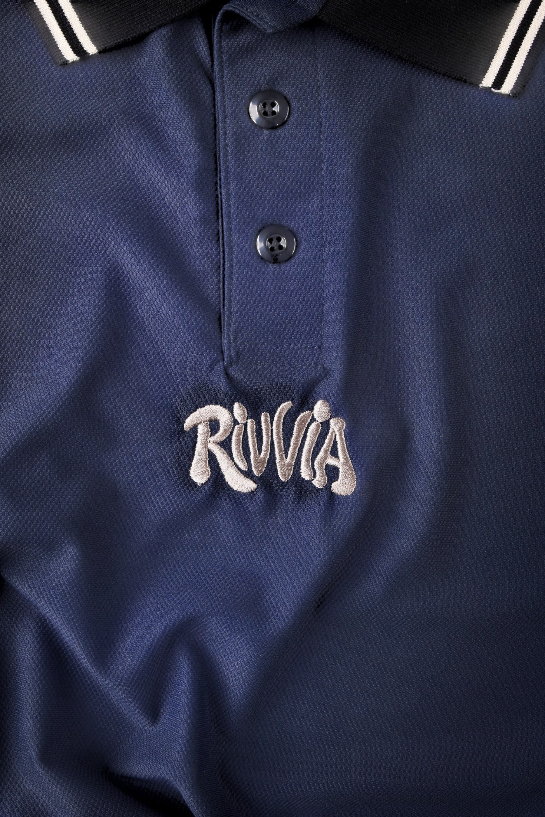 Keel Surf & Supply navy blue polo shirt with black collar and white stripes, featuring embroidered logo on chest.