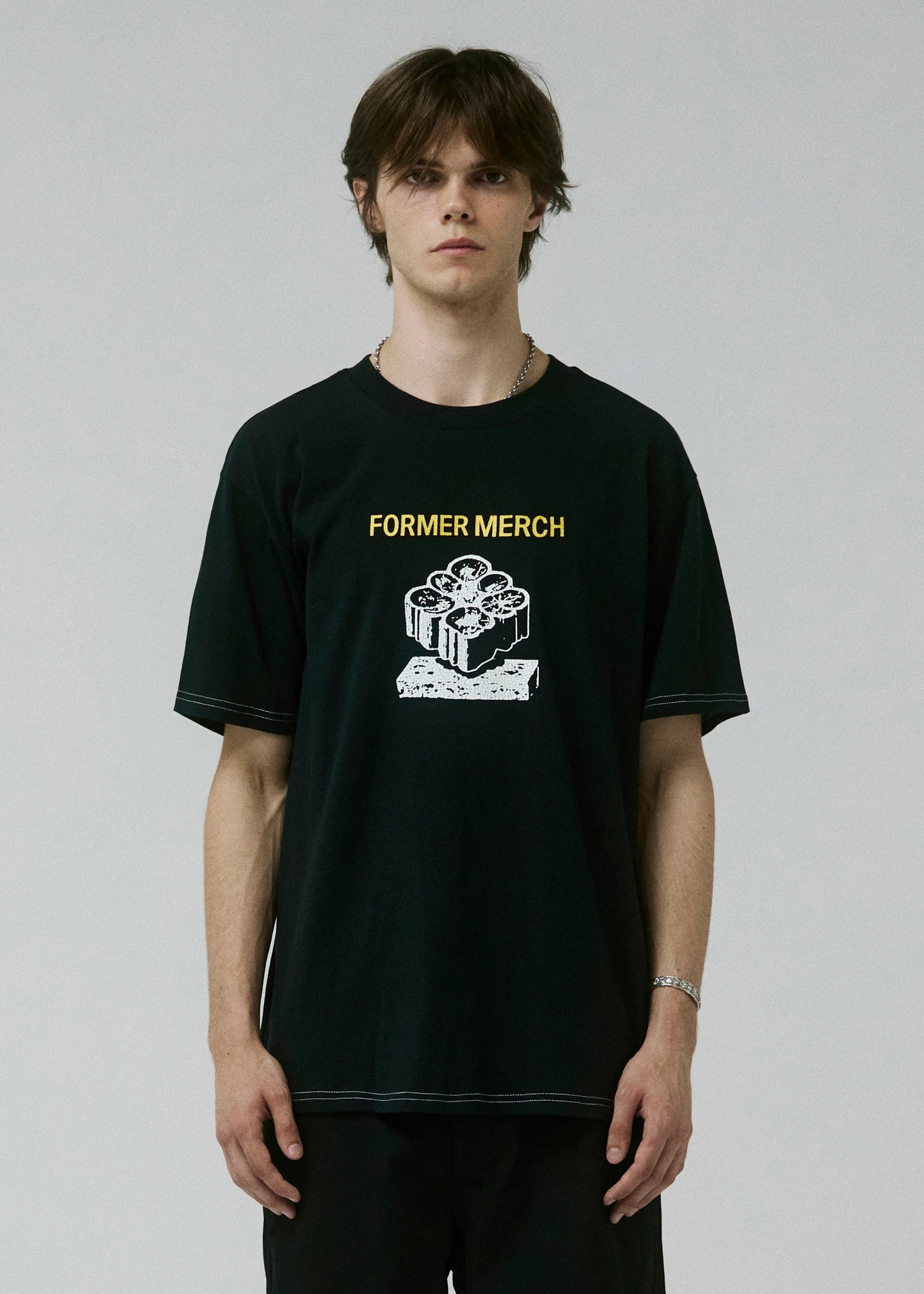 Person wearing a black t-shirt with 'Former Merch' design on a plain background