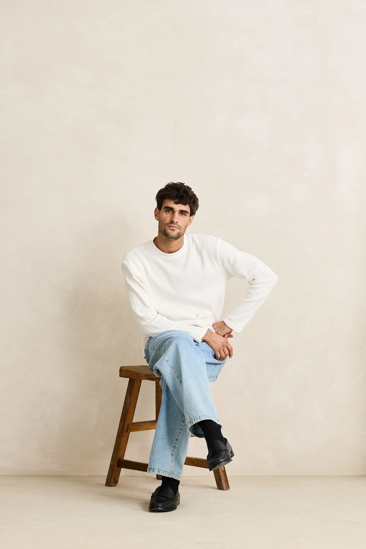 Keel Surf & Supply Rhythm Classic Waffle Knit long sleeve shirt in vintage white, worn by a man sitting on a stool.